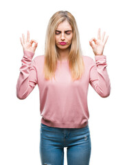 Young beautiful blonde woman wearing pink winter sweater over isolated background relax and smiling with eyes closed doing meditation gesture with fingers. Yoga concept.