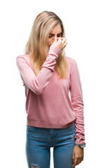 Young beautiful blonde woman wearing pink winter sweater over isolated background tired rubbing nose and eyes feeling fatigue and headache. Stress and frustration concept.