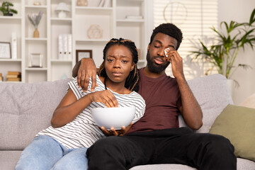Couple Watching TV With Worried Expression, Emotional Stress, Indoor Comfort And Relationship Issues. African American Adults In Casual Attire Displaying Anxiety, Home Entertainment Lifestyle.