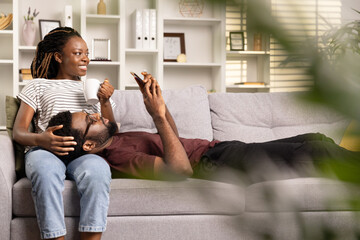 Relaxed Couple at Home, Woman with Coffee Embracing Man on Sofa, Casual Comfort, Cozy Living Room Interior