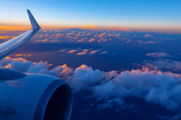 Plane engine and wing gracefully soar over clouds during the evening. Flying over Canary Islands in...