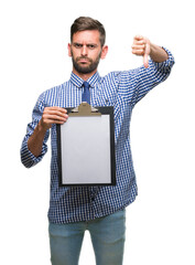 Young handsome business man holding clipboard over isolated background with angry face, negative...