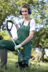 woman gardener using string lawn trimmer - obrazy, fototapety, plakaty