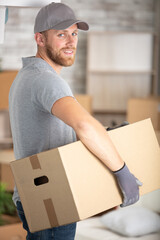 portrait of handsome bearded deliveryman carrying a box - obrazy, fototapety, plakaty
