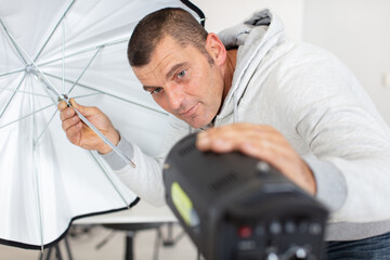 young male photographer in studio with professional lighting equipment
