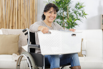 woman doint the laundry in a wheelchair - obrazy, fototapety, plakaty