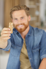 young man holding a cereal bar - obrazy, fototapety, plakaty