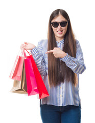 Young Chinese woman over isolated background holding shopping bags on sales very happy pointing with hand and finger