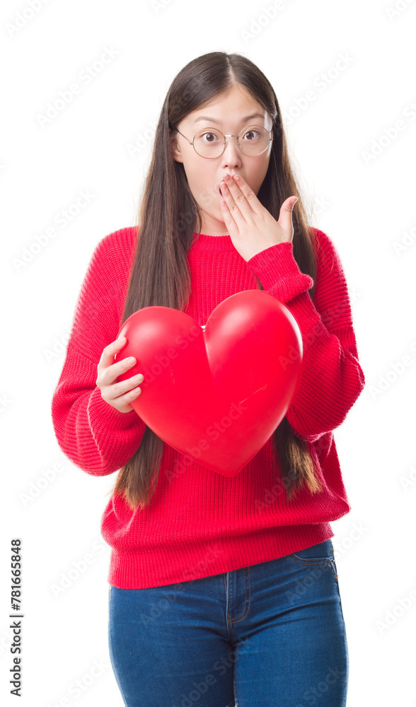 Wall mural Young Chinese woman wearing graduate uniform red heart cover mouth with hand shocked with shame for mistake, expression of fear, scared in silence, secret concept