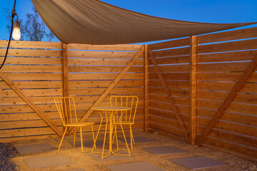 Modern yellow bistro set and privacy fence in the evening at dusk