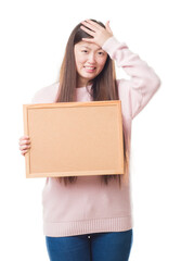 Young Chinese woman over isolated background holding corkboard stressed with hand on head, shocked with shame and surprise face, angry and frustrated. Fear and upset for mistake.