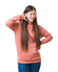 Fototapeta premium Young Chinese woman over isolated background wearing sport sweathshirt smiling doing phone gesture with hand and fingers like talking on the telephone. Communicating concepts.