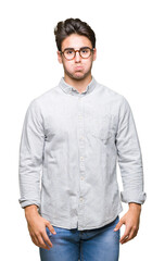 Young handsome man wearing glasses over isolated background puffing cheeks with funny face. Mouth inflated with air, crazy expression.