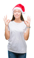Obraz na płótnie Canvas Young beautiful caucasian woman wearing christmas hat over isolated background relax and smiling with eyes closed doing meditation gesture with fingers. Yoga concept.