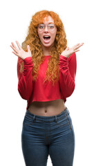 Young redhead woman wearing glasses very happy and excited, winner expression celebrating victory screaming with big smile and raised hands
