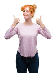 Young redhead woman success sign doing positive gesture with hand, thumbs up smiling and happy. Looking at the camera with cheerful expression, winner gesture.