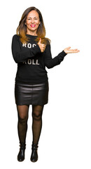 Beautiful middle age woman wearing rock and roll sweater Showing palm hand and doing ok gesture...