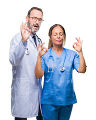 Middle age hispanic doctors partners couple wearing medical uniform over isolated background relax and smiling with eyes closed doing meditation gesture with fingers. Yoga concept.