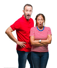 Middle age hispanic couple in love over isolated background afraid and shocked with surprise...