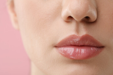 Woman wearing beautiful lip gloss on pink background, closeup
