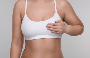 Mammology. Woman doing breast self-examination on light grey background, closeup