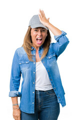 Beautiful middle age woman wearing sport cap over isolated background surprised with hand on head...