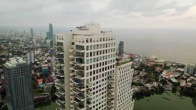 Aerial drone of modern residential skyscraper with green terraces in urban landscape. Overhead view eco-friendly architecture blending with high-density city living, promoting sustainability.