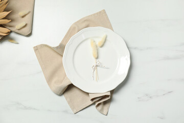 Elegant plate with spikes and napkin on white marble table, top view