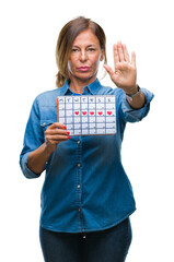 Middle age senior hispanic woman holding menstruation calendar over isolated background with open hand doing stop sign with serious and confident expression, defense gesture