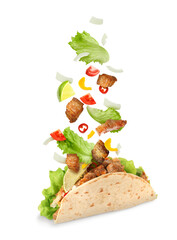 Naklejka premium Delicious taco with flying ingredients on white background