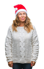 Middle age senior hispanic woman wearing christmas hat over isolated background smiling looking side and staring away thinking.