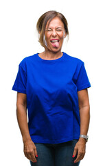 Middle age senior hispanic woman over isolated background sticking tongue out happy with funny expression. Emotion concept.