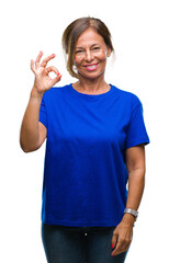 Middle age senior hispanic woman over isolated background smiling positive doing ok sign with hand and fingers. Successful expression.