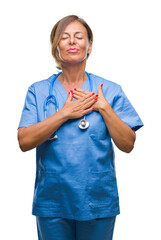 Middle age senior nurse doctor woman over isolated background smiling with hands on chest with closed eyes and grateful gesture on face. Health concept.