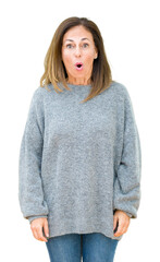 Beautiful middle age woman wearing winter sweater over isolated background afraid and shocked with...