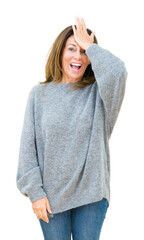 Beautiful middle age woman wearing winter sweater over isolated background surprised with hand on...