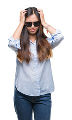 Young asian woman wearing sunglasses over isolated background suffering from headache desperate and stressed because pain and migraine. Hands on head.