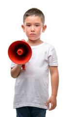 Dark haired little child holding megaphone with a confident expression on smart face thinking...