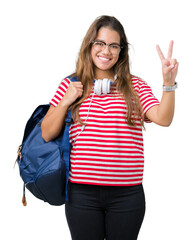 Young beautiful brunette student woman wearing headphones and backpack over isolated background smiling with happy face winking at the camera doing victory sign. Number two.