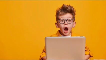 a surprised boy with glasses using laptop, sitting at the desk, solid yellow background
