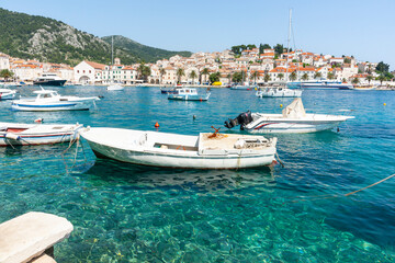 Boats at tied up in harbour with picturesque waterfront and town across bay Croatia