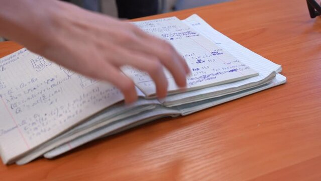 Students fold open notebooks in stack with solving exam equations, homework the of wooden desk Pupils handing over homework to teacher in class Testing knowledge in physics