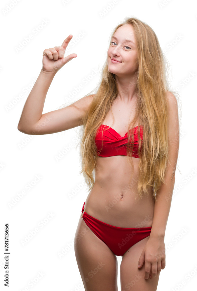 Poster blonde teenager woman wearing red bikini smiling and confident gesturing with hand doing size sign w