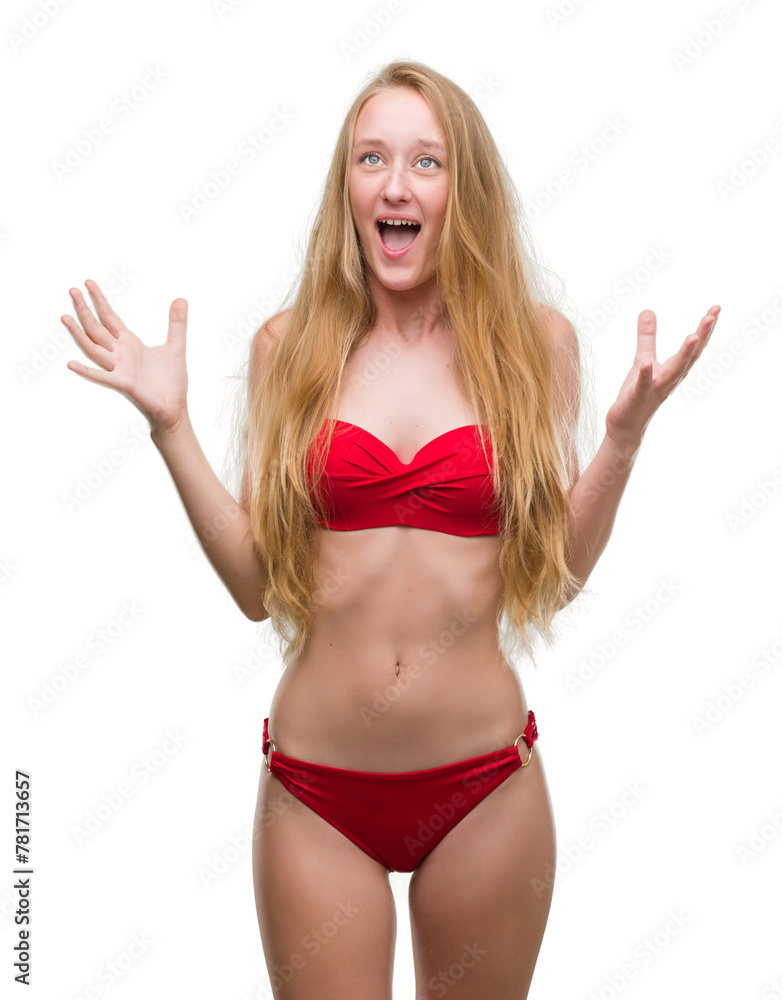 Poster Blonde teenager woman wearing red bikini crazy and mad shouting and yelling with aggressive expression and arms raised. Frustration concept.