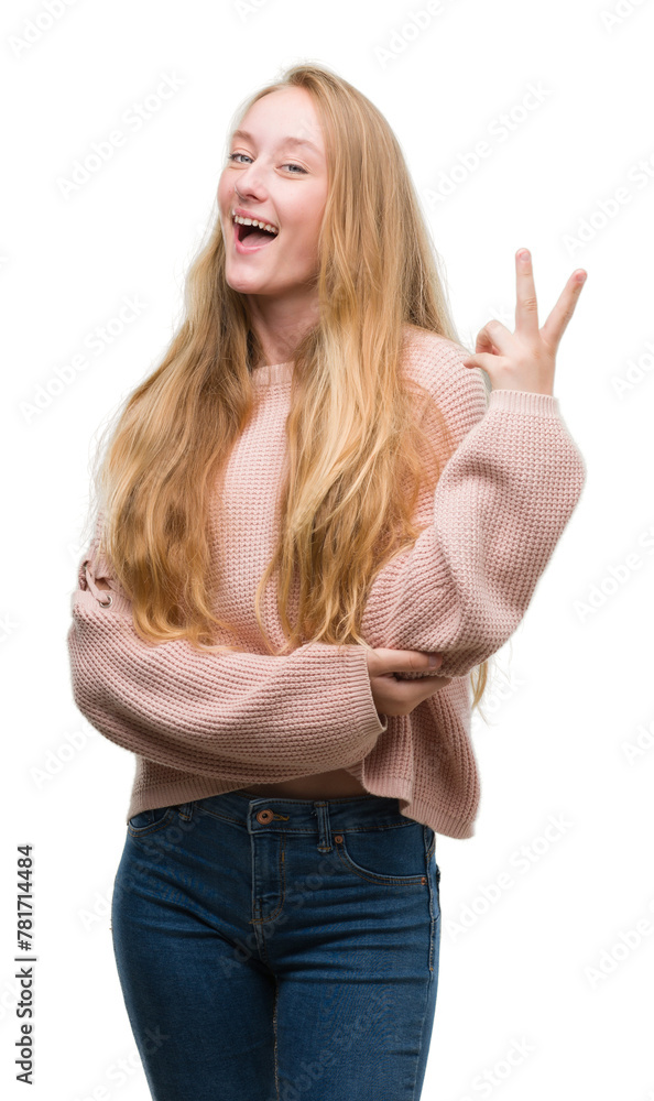 Poster blonde teenager woman wearing pink sweater smiling with happy face winking at the camera doing victo