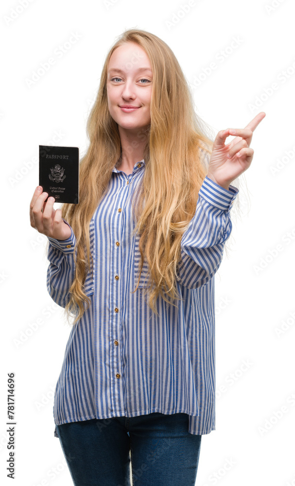 Poster blonde teenager woman holding passport of unites states of america very happy pointing with hand and