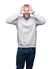 Fototapeta premium Young handsome man wearing sweatshirt over isolated background doing ok gesture like binoculars sticking tongue out, eyes looking through fingers. Crazy expression.