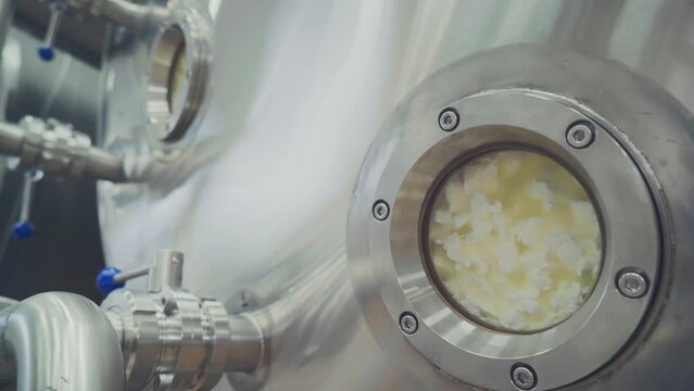 Processing of Cows Milk. Manufacturing of Dairy Based Products. Cottage Cheese. Milk Boiling process. Curd Inside a Tank. Coagulation Process. Advanced Equipment. Close up. Modern Facility
