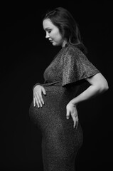 Black and white portrait of pregnant female in sequin dress with hands near pregnant belly.