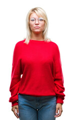 Young beautiful blonde woman wearing sweater and glasses over isolated background with serious expression on face. Simple and natural looking at the camera.